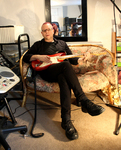 Paul Zawadzki sitting in chair playing guitar